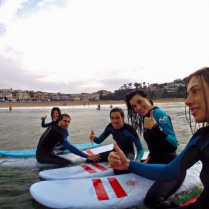 Alumnos con tablas de surf con la Escuela de Surf los Locos en la Playa de la Concha en Suances