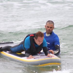 Alumno ciego con un monitor de la Escuela de Surf Surfadictos en San Vicente de la Barquera en Cantabria