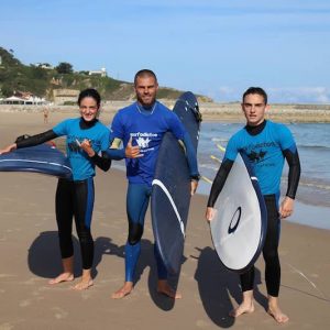 Monitor con dos alumnos de la Escuela de Surf Surfadictos en San Vicente de la Barquera en Cantabria