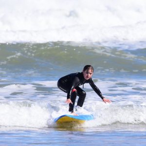 Niña haciendo un curso de surf de iniciación con la Escuela Cántabra de Surf en Somo