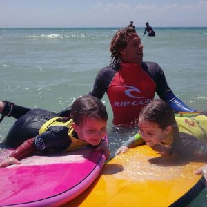 Monitor con dos niñas con la Escuela de Surf Kotadalu en la Playa de El Palmar en Vejer de la Frontera en la provincia de Cádiz