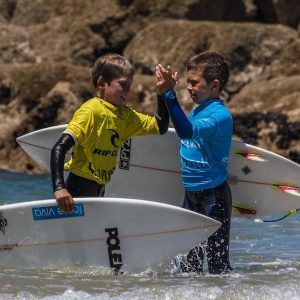 Alumnos de la Escuela de Surf Costa Norte dandose la mano en San Vicente de la Barquera