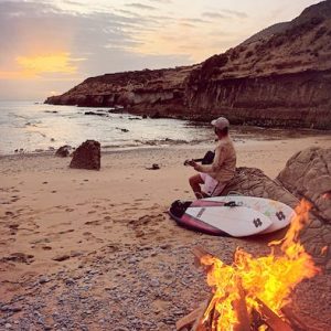 Surfista tocando la guitarra en la playa en el País Vasco