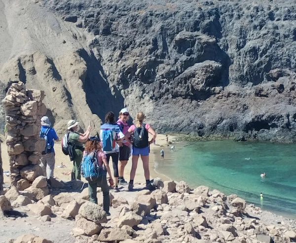 Senderistas cerca de una playa con la monitora de guía lanzarote